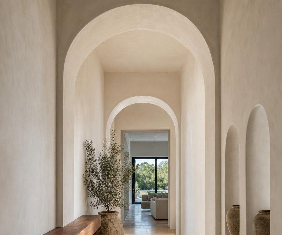 Arched hallway with smooth plaster-look walls leading to a living room