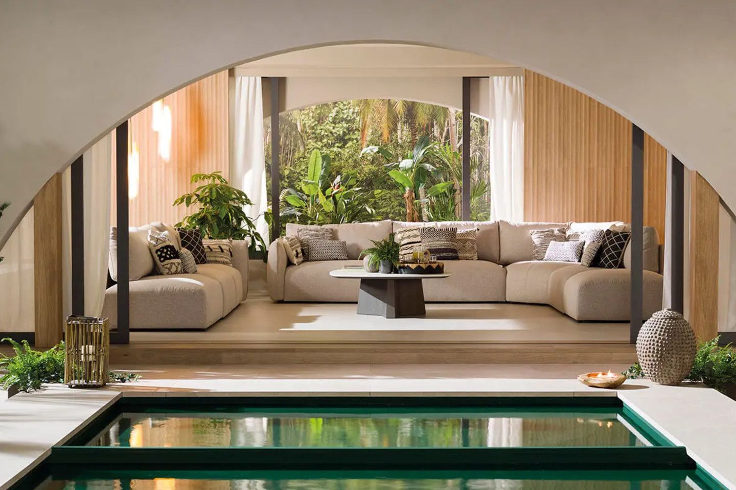 Living room seen through an arch, with a pool in front